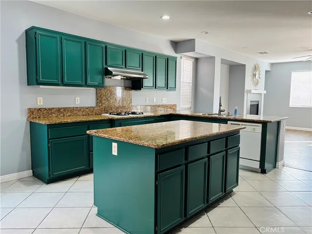 a kitchen with kitchen island granite countertop a sink dishwasher stove and cabinets