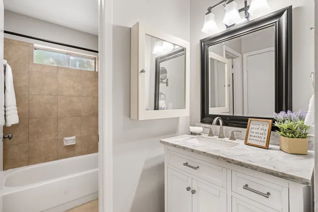a bathroom with a granite countertop sink a mirror a vanity and a bathtub