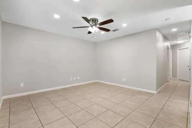 an empty room with ceiling fan and window