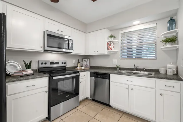 a kitchen with granite countertop white cabinets sink and stainless steel appliances