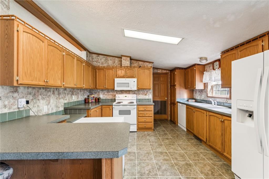 176 Seger Road Derry, PA 15627 - Photo 11 of 41 a kitchen with stainless steel appliances granite countertop a refrigerator a sink dishwasher a stove with wooden cabinets and floor