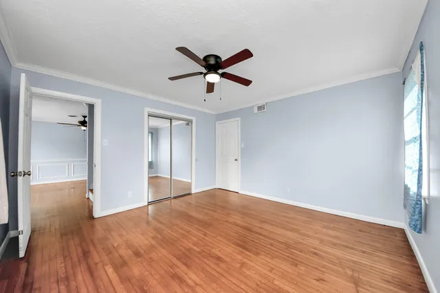 a view of empty room with wooden floor and fan