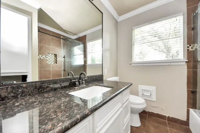 a bathroom with a granite countertop sink mirror vanity and a toilet