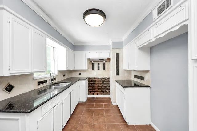 a kitchen with granite countertop a sink and cabinets