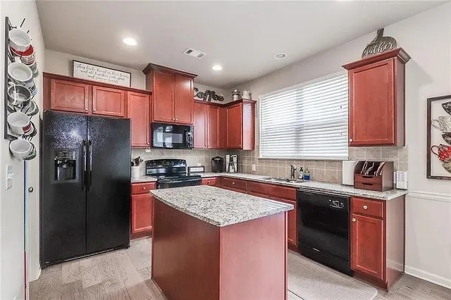 a kitchen with stainless steel appliances granite countertop a refrigerator a sink a stove a microwave and wooden cabinets