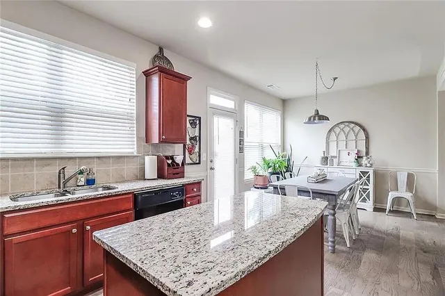 a kitchen with granite countertop kitchen island a sink cabinets and window