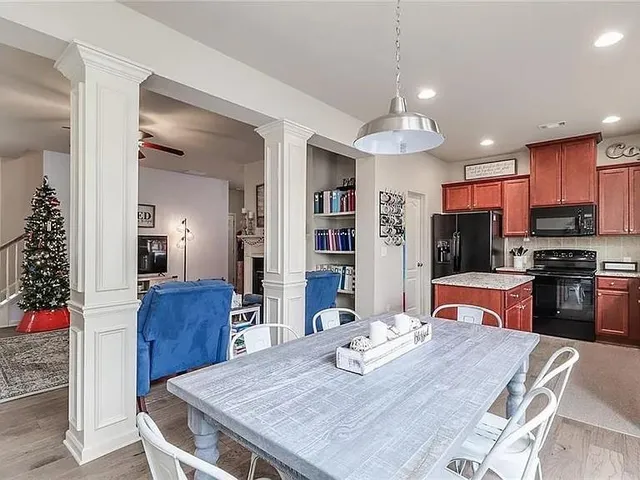 a kitchen with stainless steel appliances granite countertop a dining table chairs and refrigerator