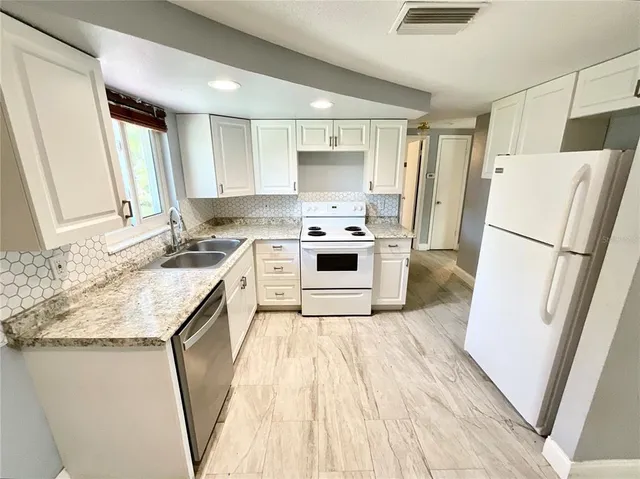 a kitchen with a sink a refrigerator a stove top oven and a window