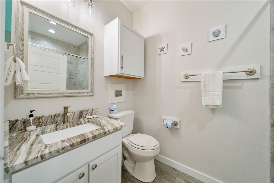 15113 Kokomo Drive Corpus Christi, TX 78418 - Photo 12 of 25 a bathroom with a granite countertop sink a toilet and a mirror