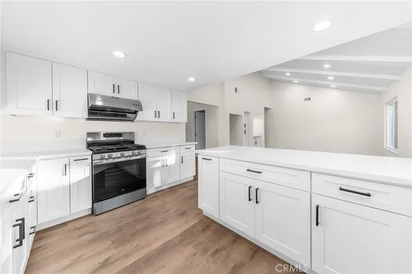 a kitchen with stainless steel appliances kitchen island wooden floors and white cabinets