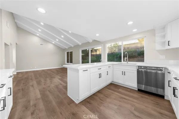 a kitchen with stainless steel appliances granite countertop a stove a sink and white cabinets with wooden floor
