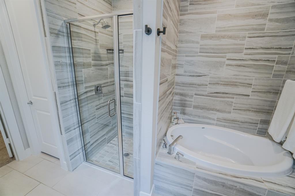 1309 Old Rocksprings Pass Mansfield, TX 76063 - Photo 16 of 36 Shower with glass enclosure and a separate soaking tub, both surrounded by horizontal gray-toned tile