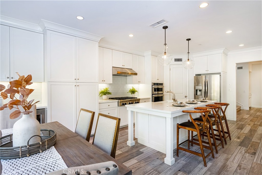 57 Bandana Irvine, CA 92602 - Photo 7 of 32 a kitchen with stainless steel appliances granite countertop a refrigerator a stove a sink dishwasher and a dining table with wooden floor
