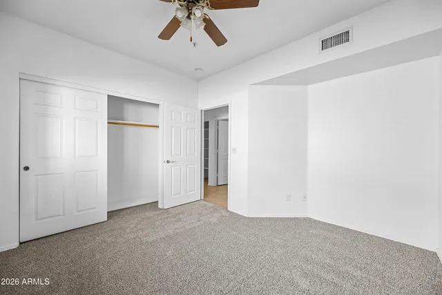 an empty room with window and ceiling fan