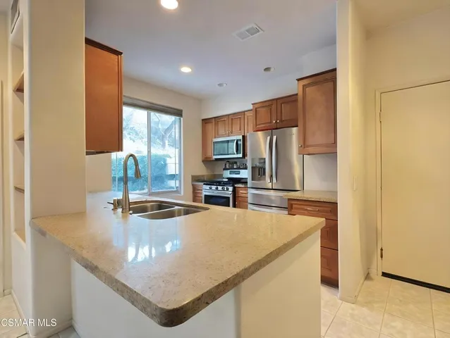 a kitchen with stainless steel appliances granite countertop a sink a stove and a refrigerator