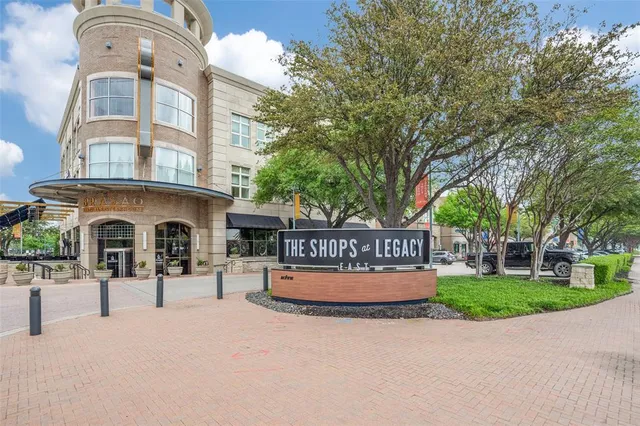 a front view of a building with garden and trees