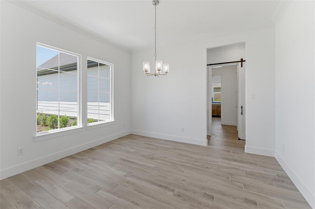 815 Vly Rdg Road Van Alstyne, TX 75495 - Photo 7 of 29 Spacious room featuring wood-finish flooring, white walls, and a contemporary chandelier