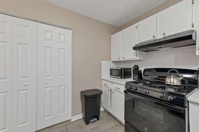 a kitchen with white cabinets and black appliances