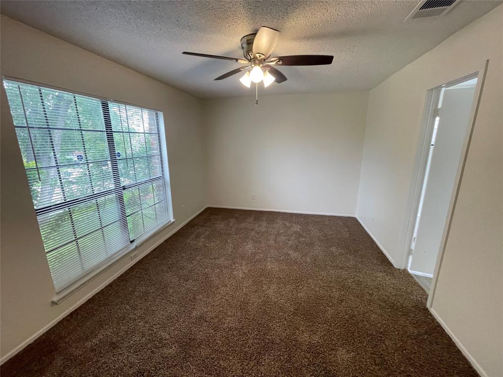 9415 Rutherglen Drive Dallas, TX 75227 - Photo 13 of 18 en empty room with windows and ceiling fan