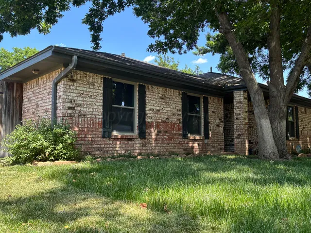 a view of a house with a small yard and a large tree