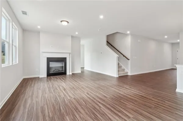 an empty room with wooden floor fireplace and windows