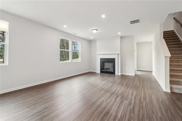 an empty room with wooden floor fireplace and windows