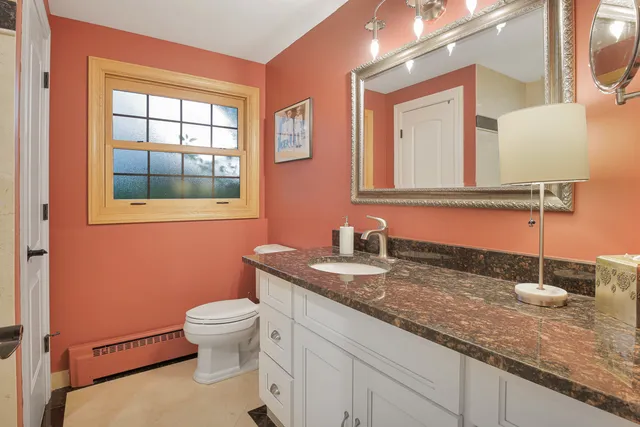 a bathroom with a granite countertop sink a toilet and a mirror