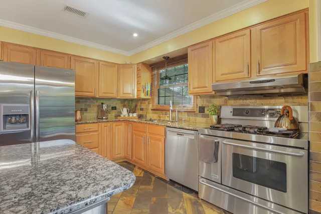 a kitchen with stainless steel appliances granite countertop a stove a sink and a refrigerator