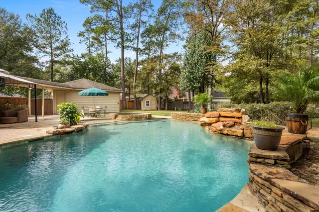 a view of swimming pool with lawn chairs and plants