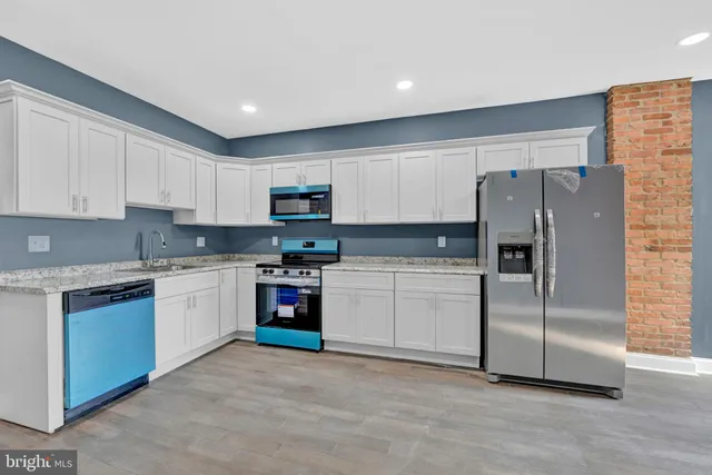 a kitchen with granite countertop a refrigerator sink and white cabinets