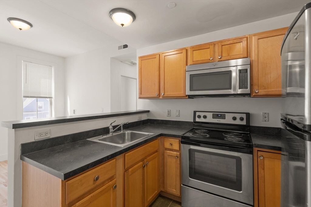 145 Lewis Street Lynn, MA 01902 - Photo 8 of 32 a kitchen with stainless steel appliances granite countertop a sink stove microwave and cabinets