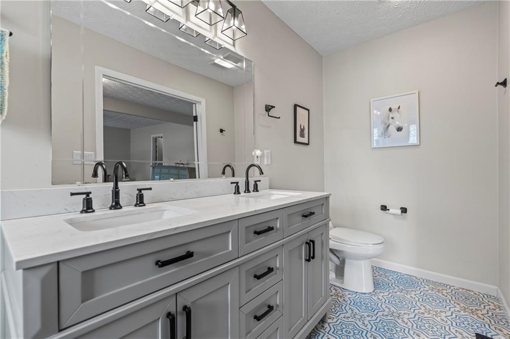 2150 Smyrna Ridge Court Southwest Conyers, GA 30094 - Photo 52 of 125 a spacious bathroom with a double vanity sink a toilet and a mirror