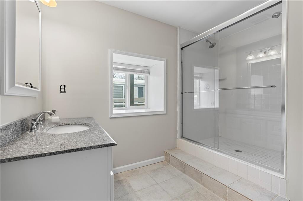 2150 Smyrna Ridge Court Southwest Conyers, GA 30094 - Photo 61 of 125 a bathroom with a granite countertop sink a shower and a mirror