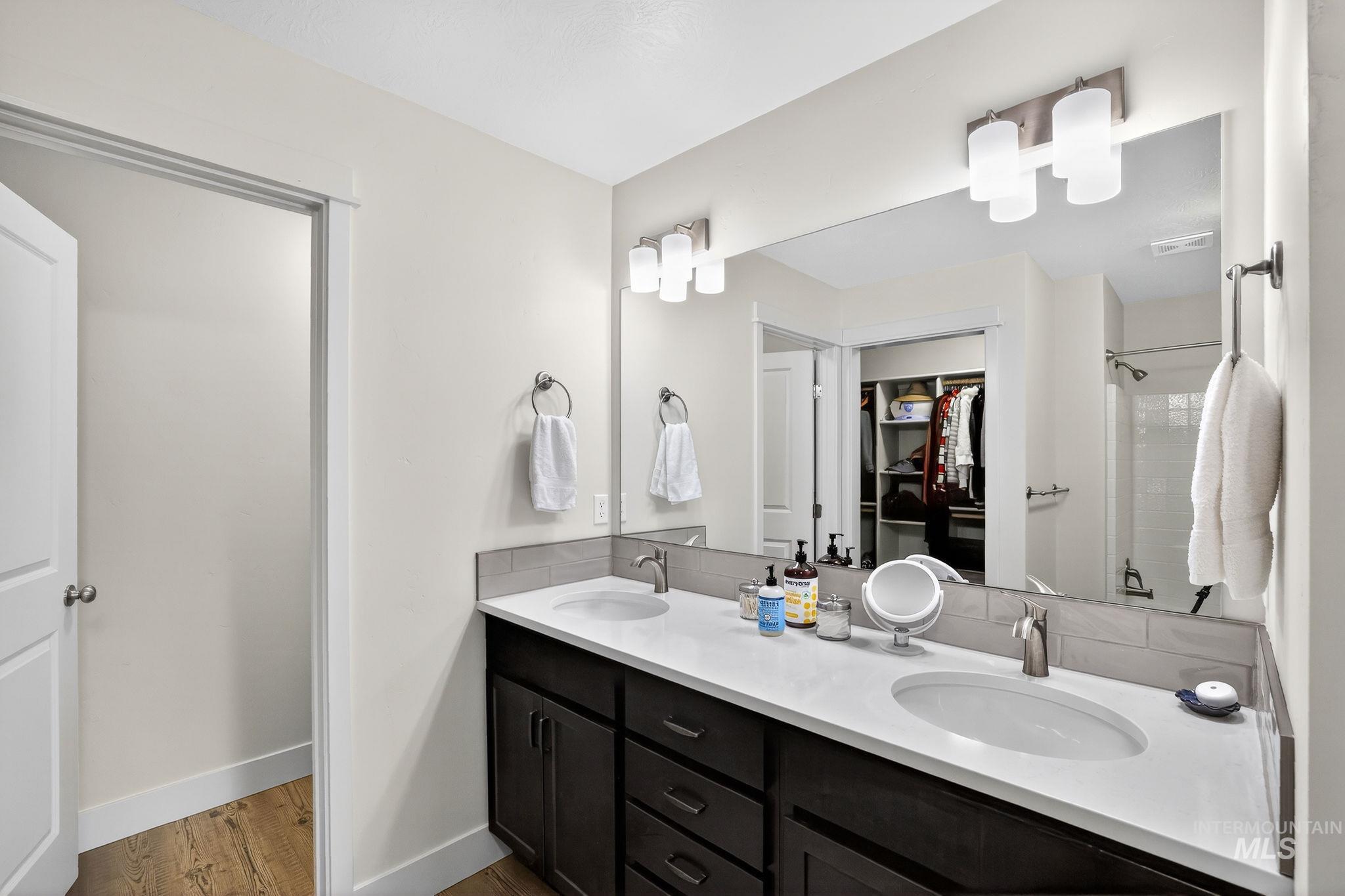 311 Broken Ridge Way McCall, ID 83638 - Photo 29 of 44 Double vanity featuring undermount sinks, white countertops, and dark wood cabinetry