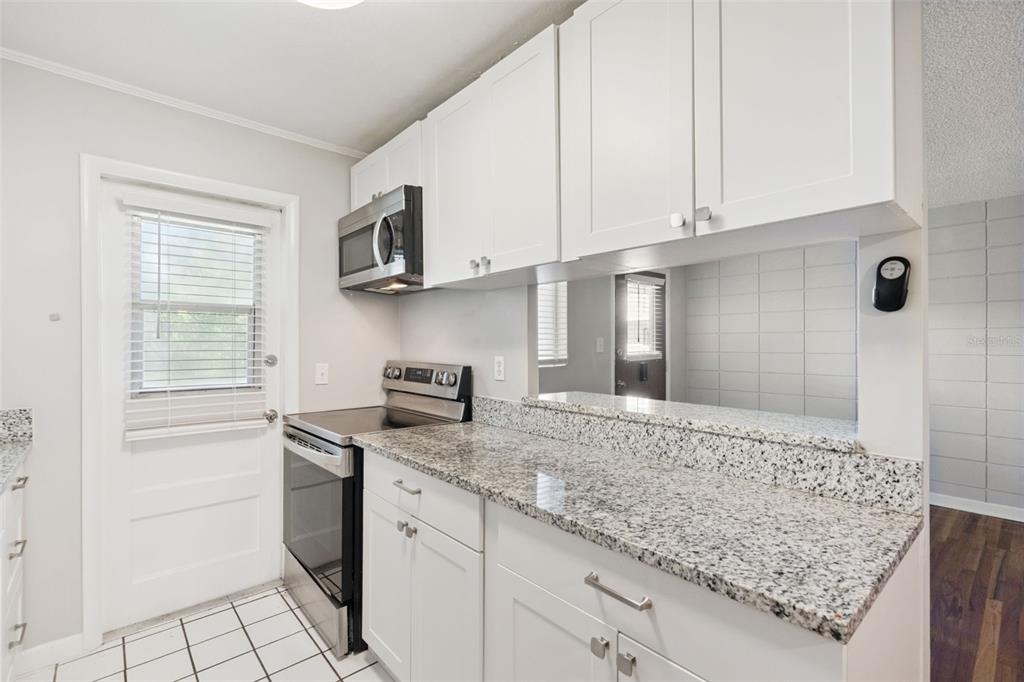 320 Lakeview Street, Unit 213 Orlando, FL 32804 - Photo 11 of 24 a kitchen with stainless steel appliances granite countertop a sink stove and microwave