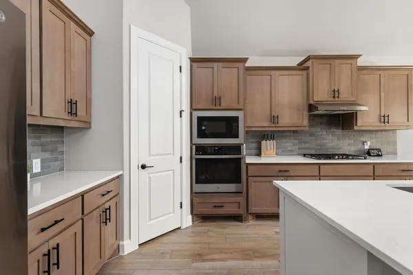a kitchen with stainless steel appliances granite countertop a sink a stove a refrigerator cabinets and wooden floor