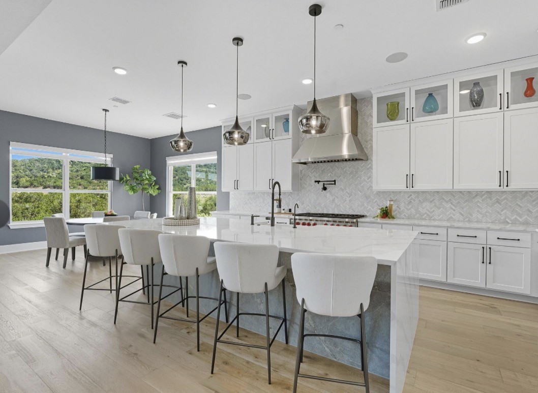 6817 Davenport Divide Road Austin, TX 78738 - Photo 7 of 28 a kitchen with stainless steel appliances granite countertop a stove a sink a refrigerator a dining table and chairs with wooden floor