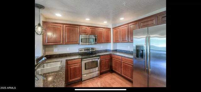a kitchen with stainless steel appliances granite countertop a stove a refrigerator and a sink