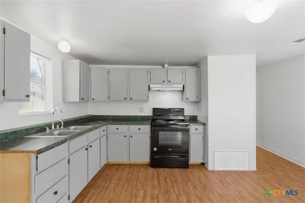 a kitchen with granite countertop a sink stove and cabinets