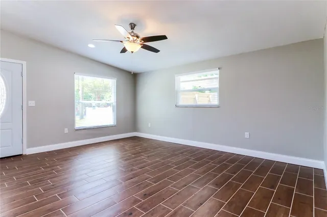a view of an empty room with wooden floor and a window