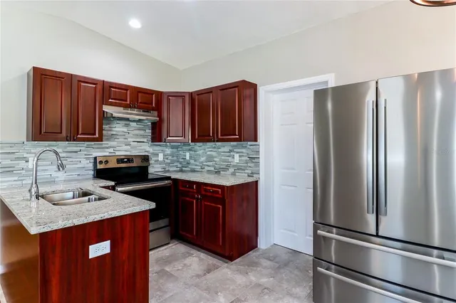 a kitchen with stainless steel appliances granite countertop a refrigerator and a sink