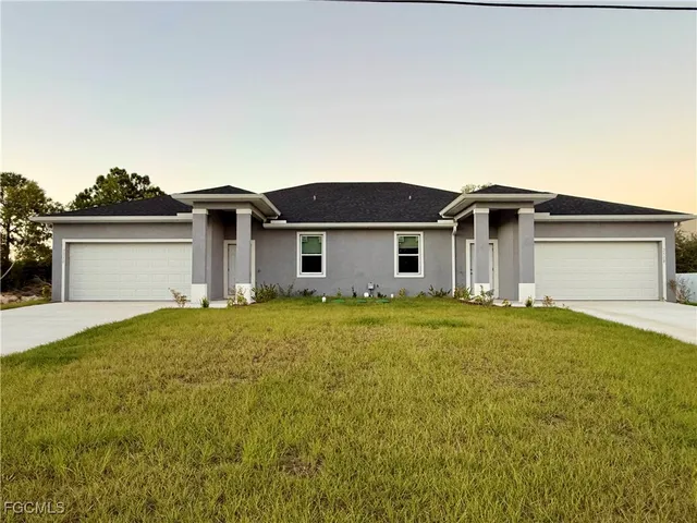 a front view of house with yard and trees in the background