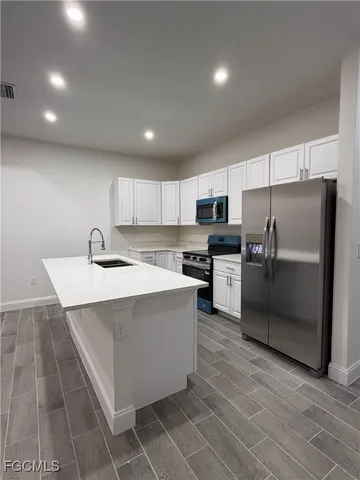 a view of kitchen with stainless steel appliances refrigerator stove microwave and cabinets