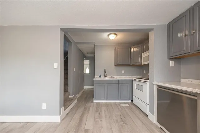 a kitchen with stainless steel appliances granite countertop a sink and cabinets with wooden floor