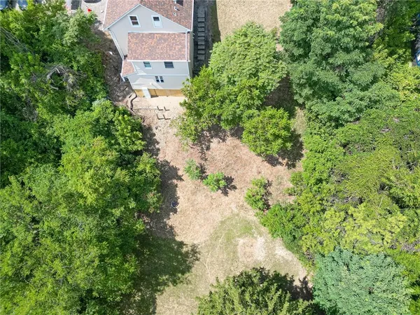 an aerial view of residential house with outdoor space and trees all around