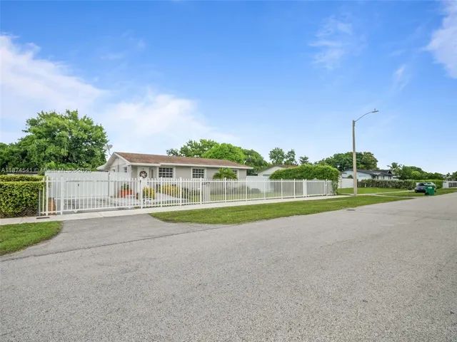 a view of big house with a big yard and large trees