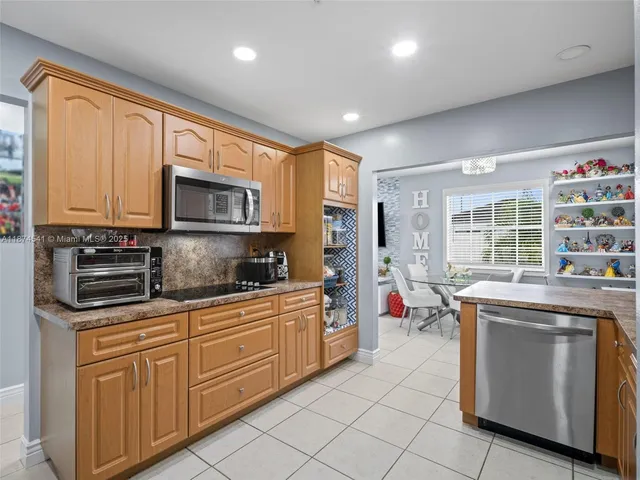 a kitchen with stainless steel appliances granite countertop a stove top oven a sink dishwasher a dining table and chairs with wooden floor