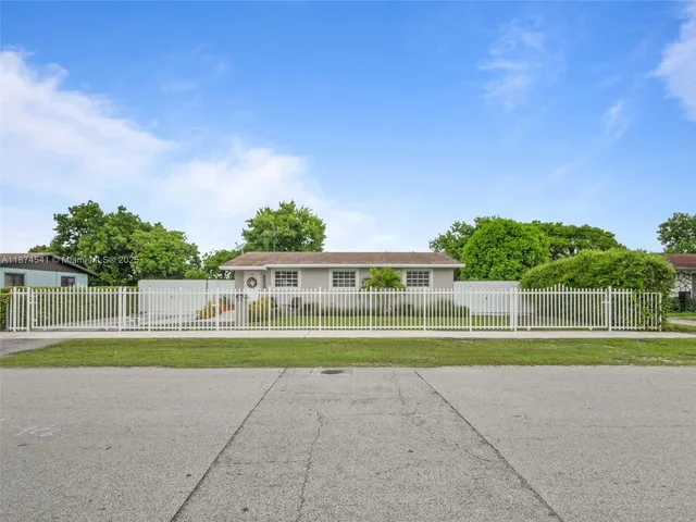 a front view of a house with a yard and a large tree