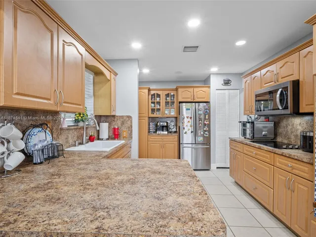 a kitchen with stainless steel appliances granite countertop a refrigerator a stove a sink dishwasher and white cabinets with wooden floor