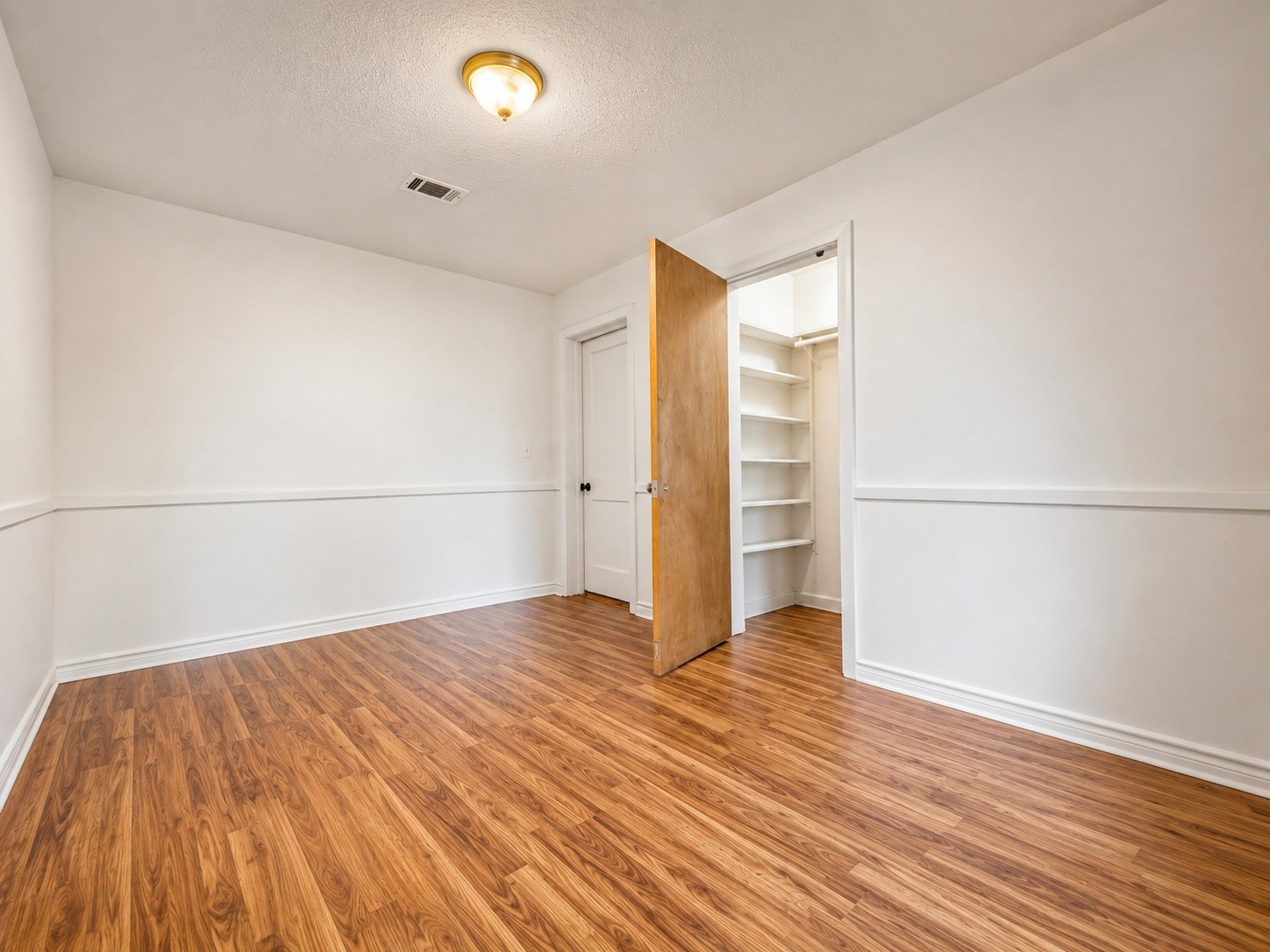 316 Riley Road Clute, TX 77531 - Photo 10 of 21 Bright and spacious bedroom with elegant wood style flooring, featuring a convenient walk-in closet with ample shelving.